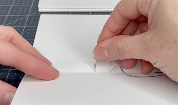 move the needle out of the signature through the next sewing station up